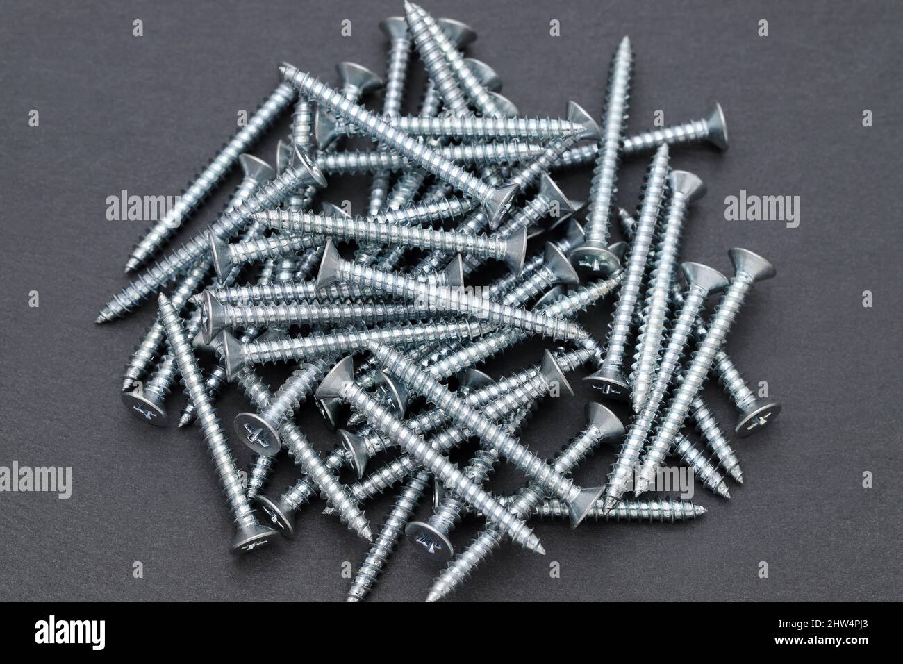 silver metallic tapping screws on black background Stock Photo