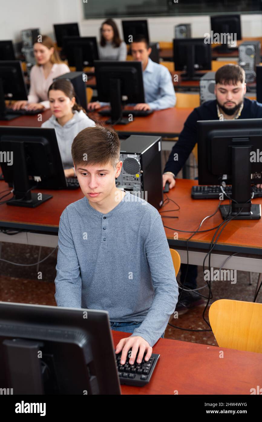Portrait of female and male students working on computers in classroom ...