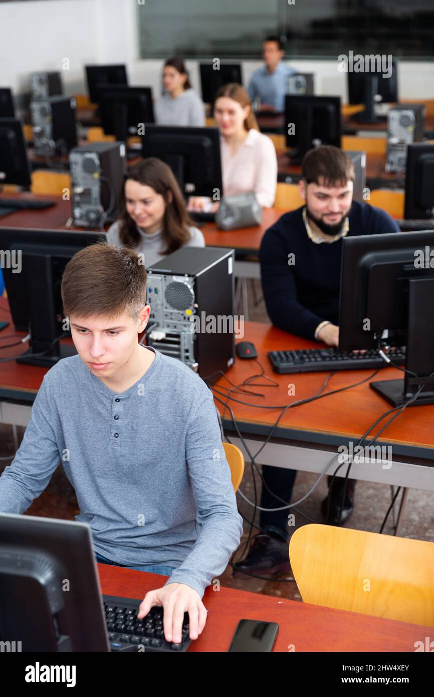 Portrait of female and male students working on computers in classroom ...