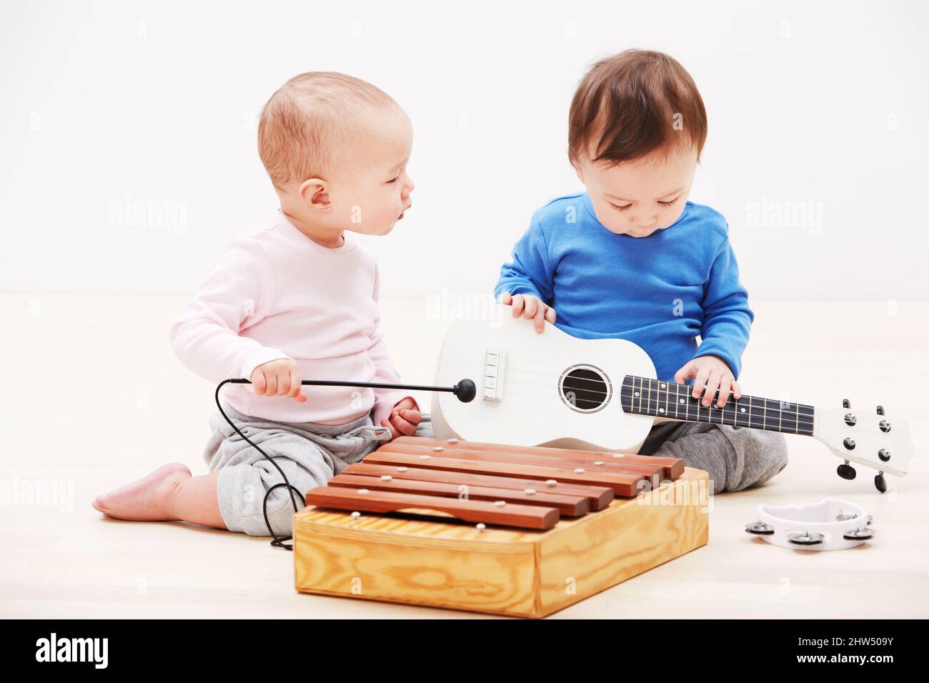 They have the makings of a successful band. Shot of two adorable babies playing with toy musical instruments. Stock Photo