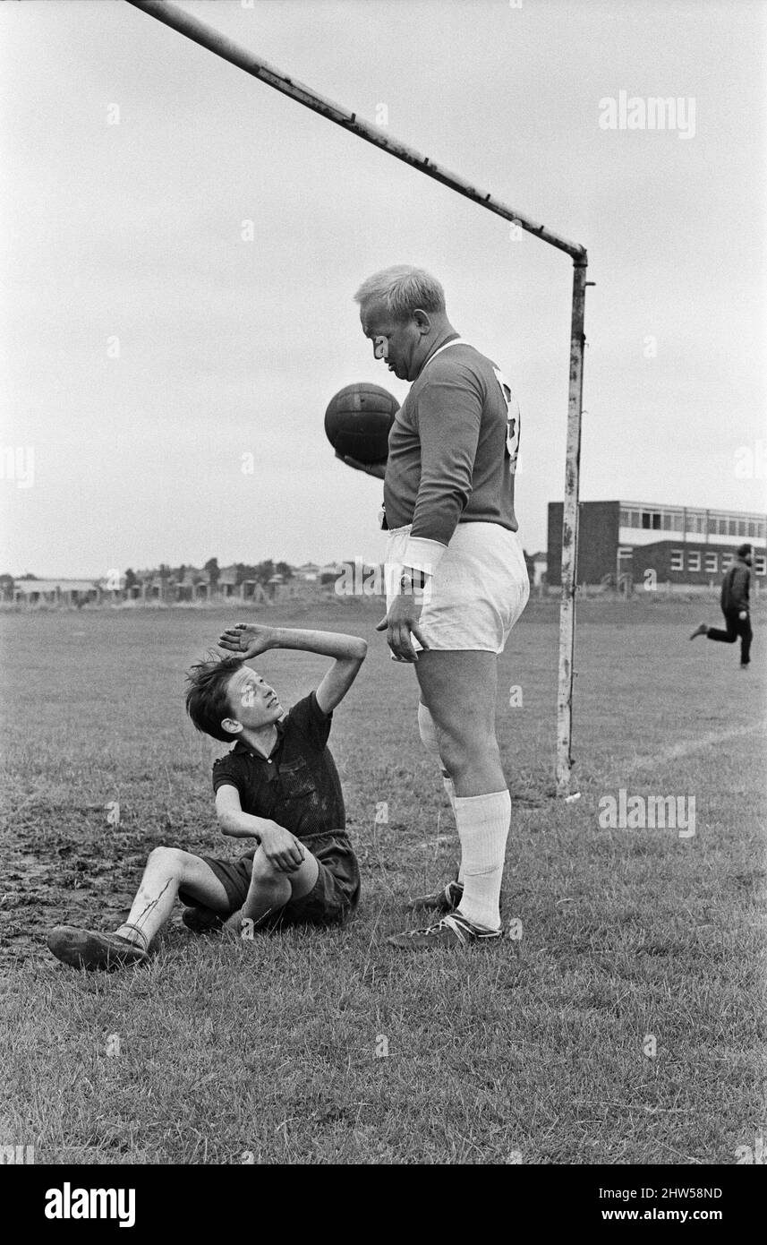 David Bradley, (aged 14) playing the part of Billy Casper, pictured with his Kestral, on the film set of the film Kes.   Here Billy Casper is playing the goalkeeper in the school football match scene.  With him is Mr Sugden, played by Brian Glover.   Mr Sugden thinks he is Bobby Charlton, wearing a Manchester United shirt, and ordering his players around the field. Kes is a 1969 release drama film directed by Ken Loach and produced by Tony Garnett. The film is based on the 1968 novel A Kestrel for a Knave, written by the Barnsley-born author Barry Hines. The film is ranked seventh in the Briti Stock Photo