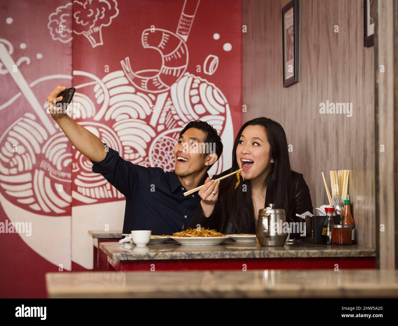 Chinese couple posing for cell phone selfie in restaurant Stock Photo