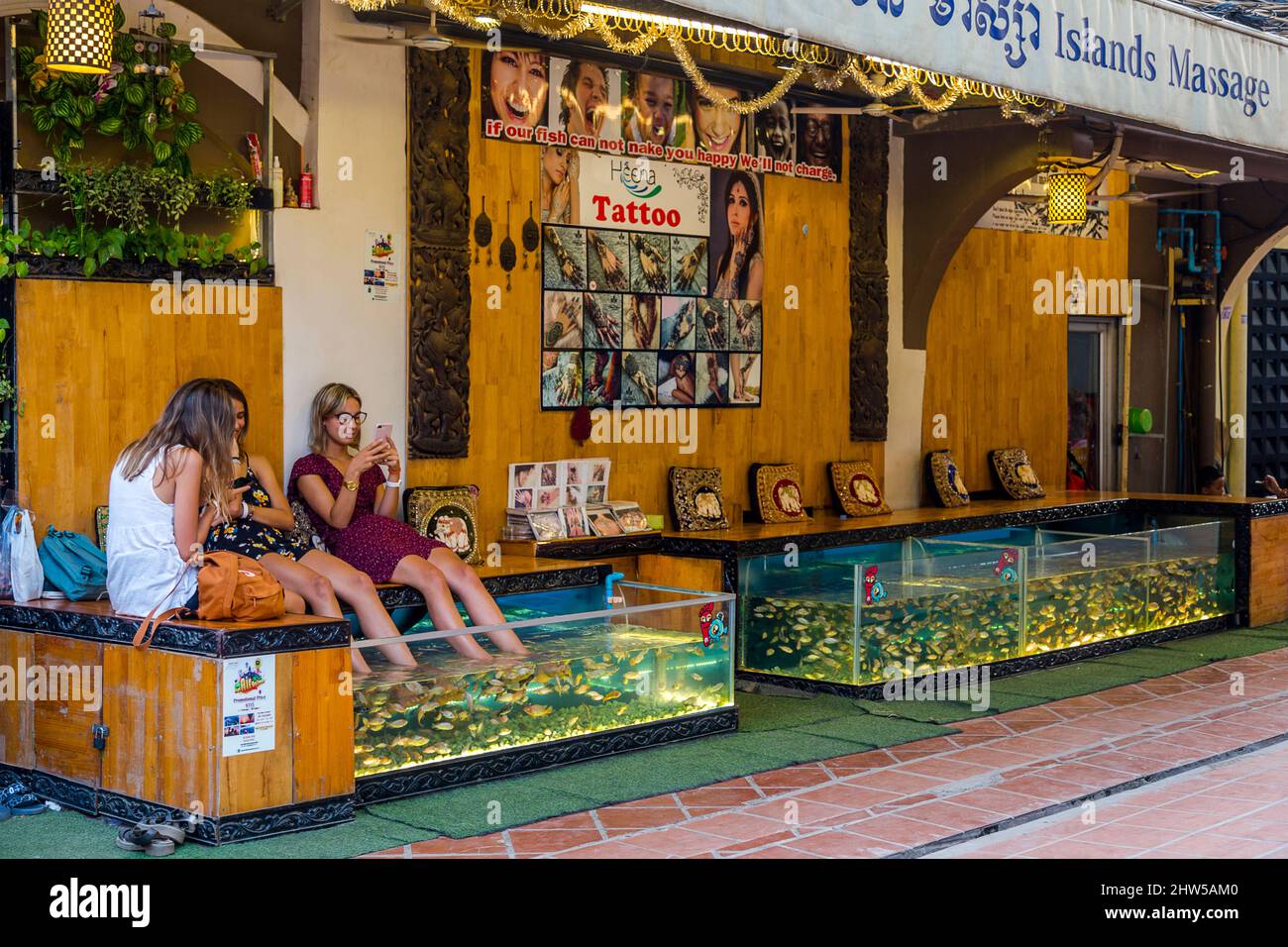 Two women soaking their feet in a fish tank with fish eating their