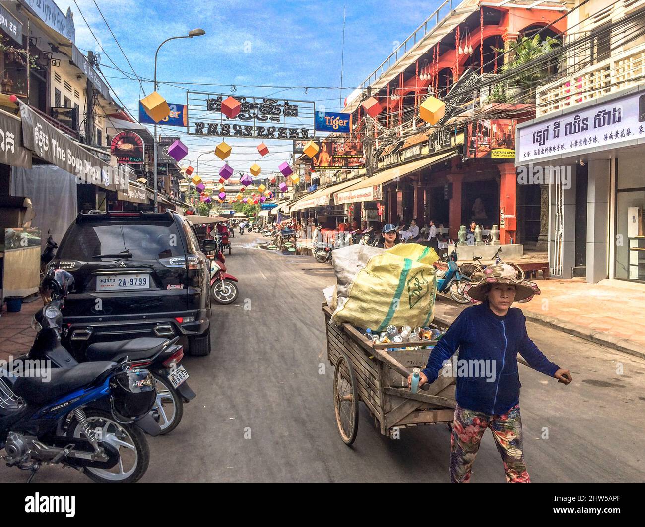 Cambodian lady pulls a cart carrying goods down the street. Stock Photo