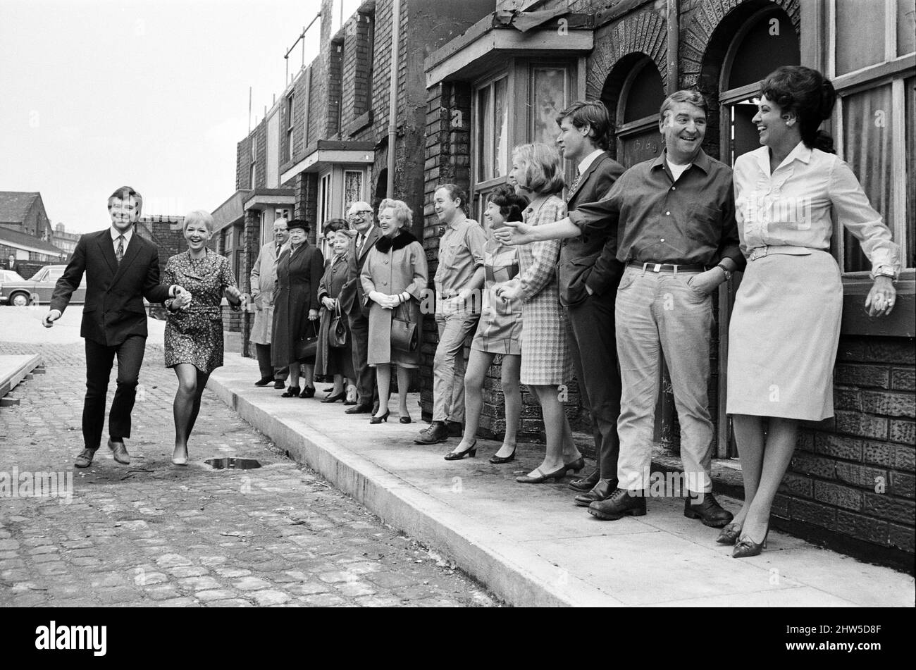 A new street setting for 'Coronation Street'. Granada TV have built an outdoor set for shooting some of the scenes. Pictured are cast members:  Cast member Dennis Tanner (Philip Lowrie) with his bride Jenny Sutton (Mitzi Rogers) after their wedding with Annie Walker (Doris Speed), Ena Sharples (Violet Carson), Emily Nugent (Eileen Derbyshire), Valerie Barlow (Anne Reid), Ken Barlow (William Roache) Len Fairclough (Peter Adamson) and Elsie Tanner (Pat Phoenix). 18th May 1968. Stock Photo