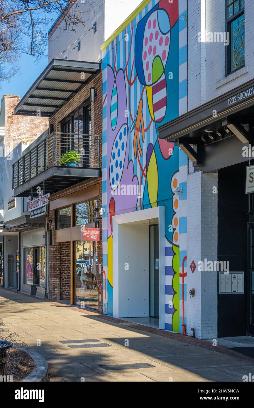 Painted facade mural called 'Levanta e Tai' (Portuguese for 'Get Up and Go') by artist Yoyo Ferro at Pop UPtown on Broadway in Uptown Columbus, GA. Stock Photo