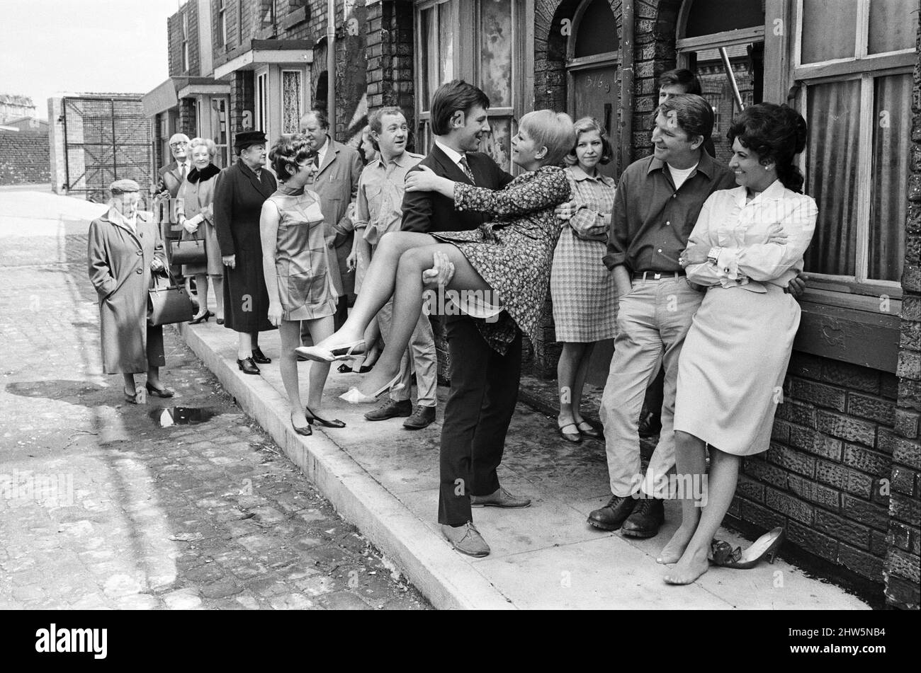 A new street setting for 'Coronation Street'. Granada TV have built an outdoor set for shooting some of the scenes. Pictured are cast members:  Cast member Dennis Tanner (Philip Lowrie) with his bride Jenny Sutton (Mitzi Rogers) after their wedding with Annie Walker (Doris Speed), Ena Sharples (Violet Carson), Emily Nugent (Eileen Derbyshire), Valerie Barlow (Anne Reid), Ken Barlow (William Roache) Len Fairclough (Peter Adamson). and Elsie Tanner (Pat Phoenix). 18th May 1968. Stock Photo