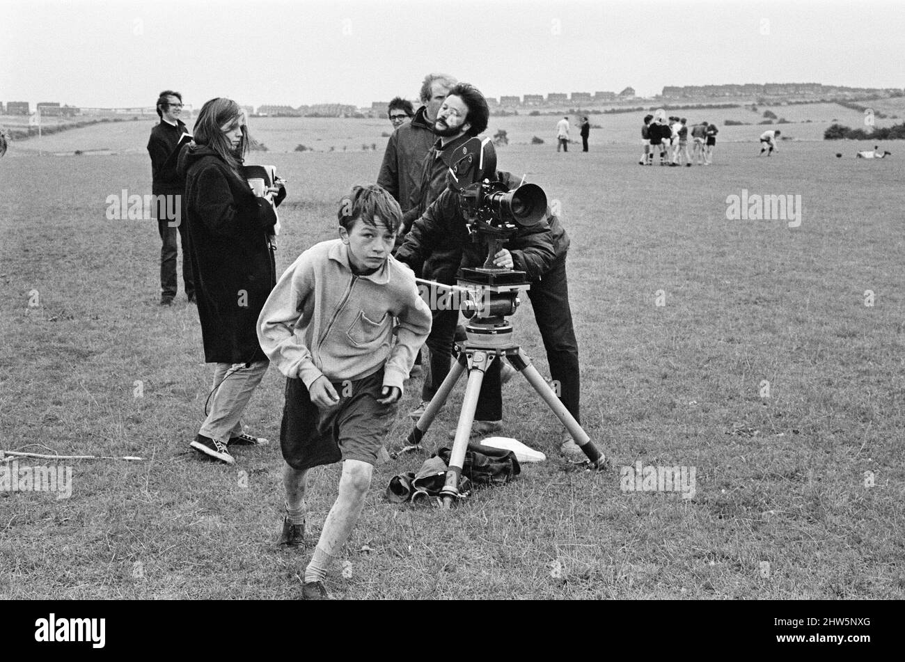 David Bradley, (aged 14) playing the part of Billy Casper, pictured with his Kestral, on the film set of the film Kes.   Here Billy Casper is running to play a football scene after talking with the film crew at the school playing field. Kes is a 1969 release drama film directed by Ken Loach and produced by Tony Garnett. The film is based on the 1968 novel A Kestrel for a Knave, written by the Barnsley-born author Barry Hines. The film is ranked seventh in the British Film Institute's Top Ten (British) Films and among the top ten in its list of the 50 films you should see by the age of 14. Stock Photo