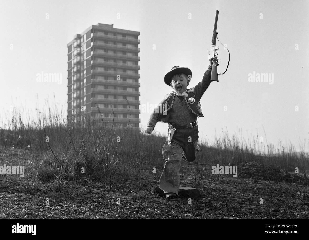 Young boy playing cowboys in Collyhurst, Manchester 14th January 1968His grandfather knew this street when tiny terraced houses stared at each other. His father remembers the bulldozers moving in. To this day it's a playground where the rubble of the past is giving way to a new frontier. Stock Photo
