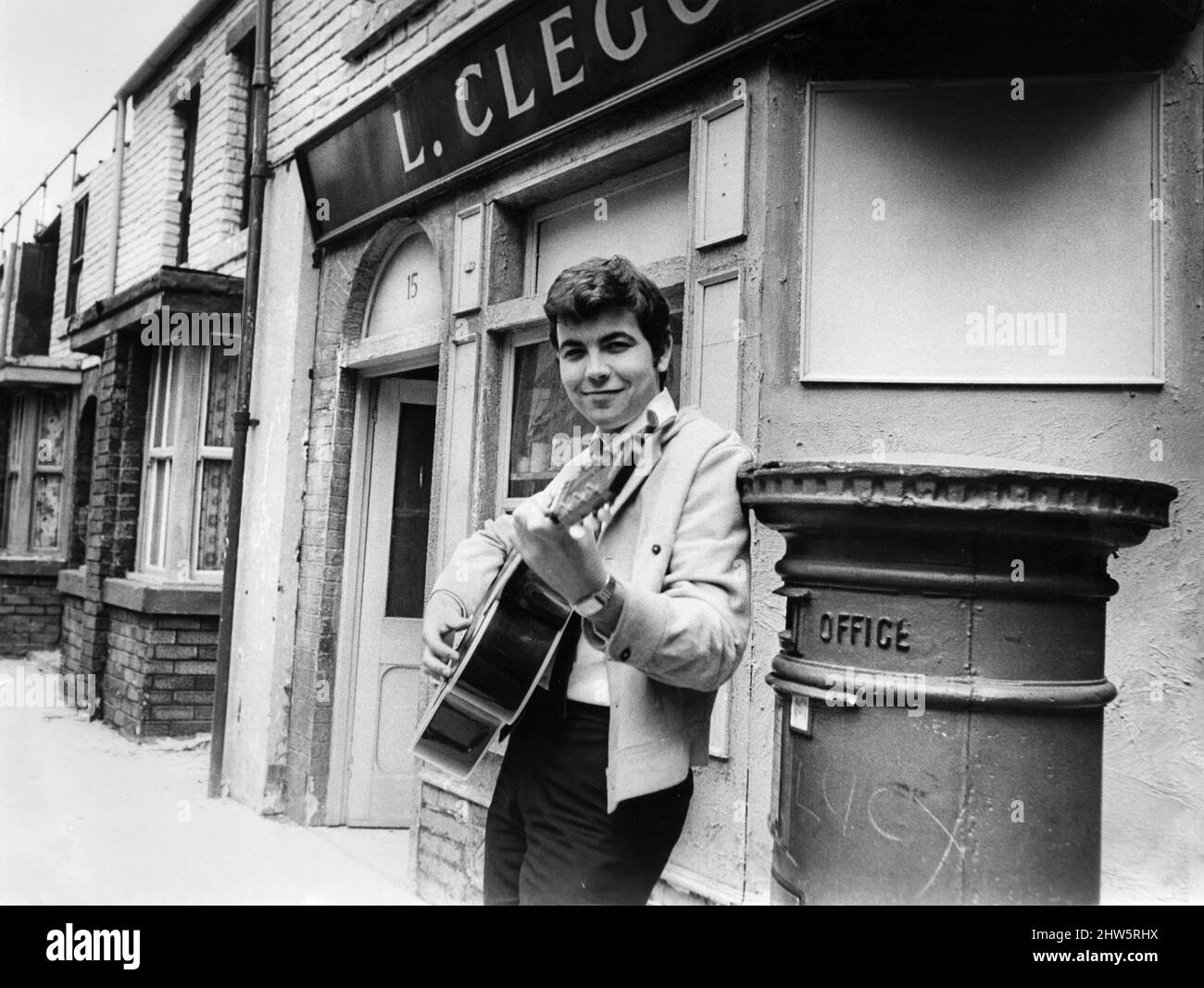 Actor Bill Kenwright who plays Gordon Clegg in the television soap opera Cornation Street, poses in the famous street with his guitar shortly before the release of his new record which he will sing on the programme.  23rd July 1968. Stock Photo