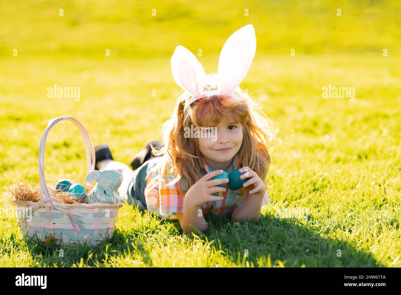 Easter bunny children laying on grass. Kids boy in bunny ears hunting