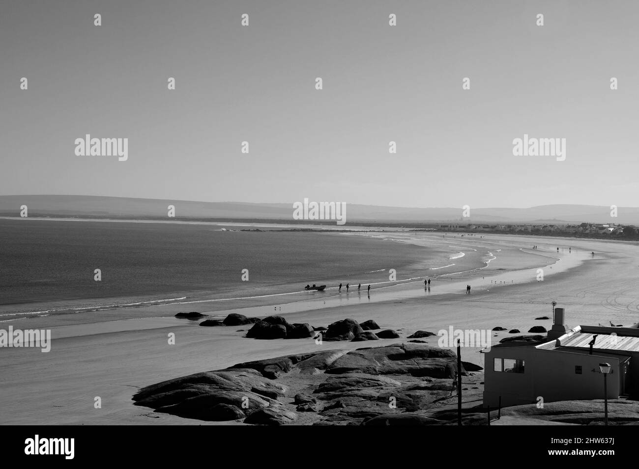 Black and white photo of people walking on the beach at Paternoster, West Coast, South Africa. Stock Photo