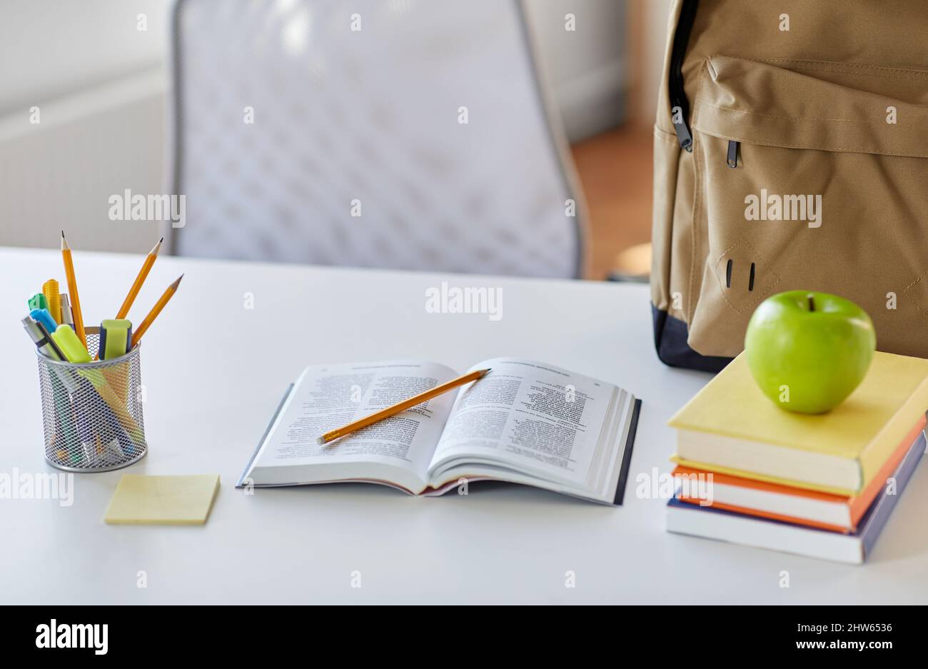 books, apple and school supplies on table at home Stock Photo
