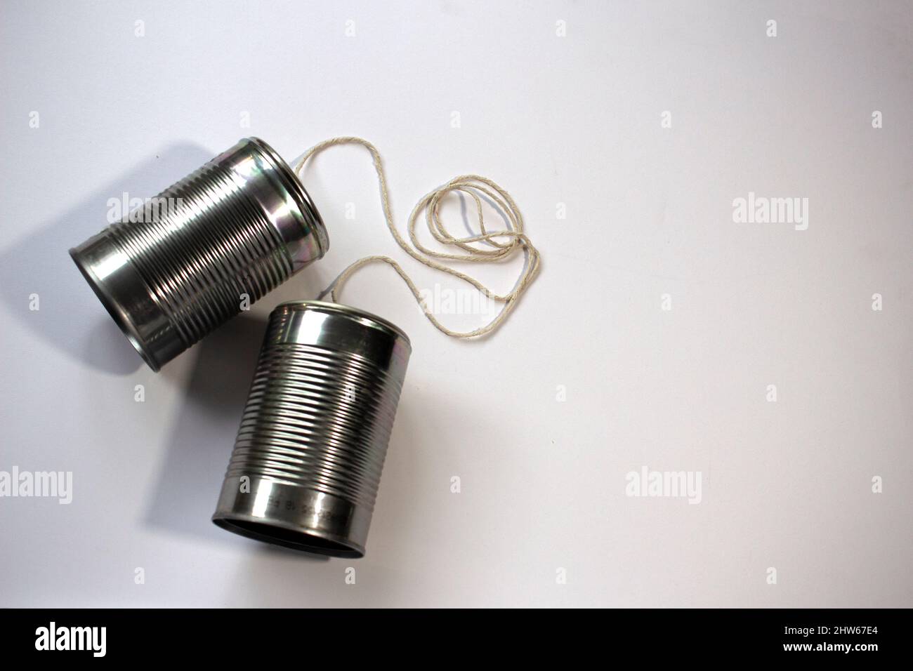 Overhead view of two tin can phones with tangled strings, suggesting miscommunication or misunderstanding. 2 of 4. Space for text Stock Photo