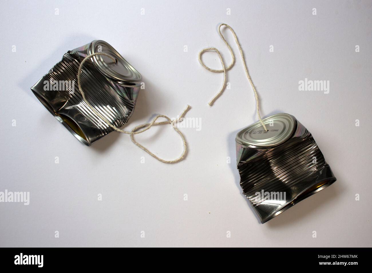 Overhead view of two crushed tin can phones with strings cut, communication breakdown and the end of a relationship. 4 of 4. Space for text Stock Photo