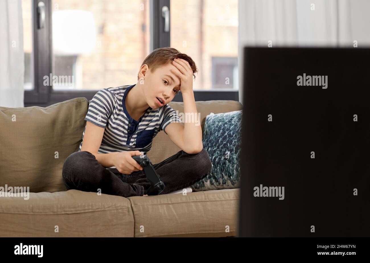 sad boy with gamepad playing video game at home Stock Photo