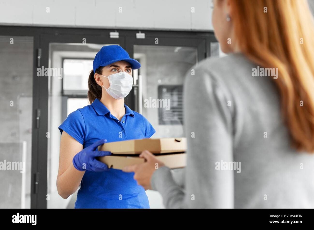 delivery girl in mask giving pizza boxes to woman Stock Photo - Alamy