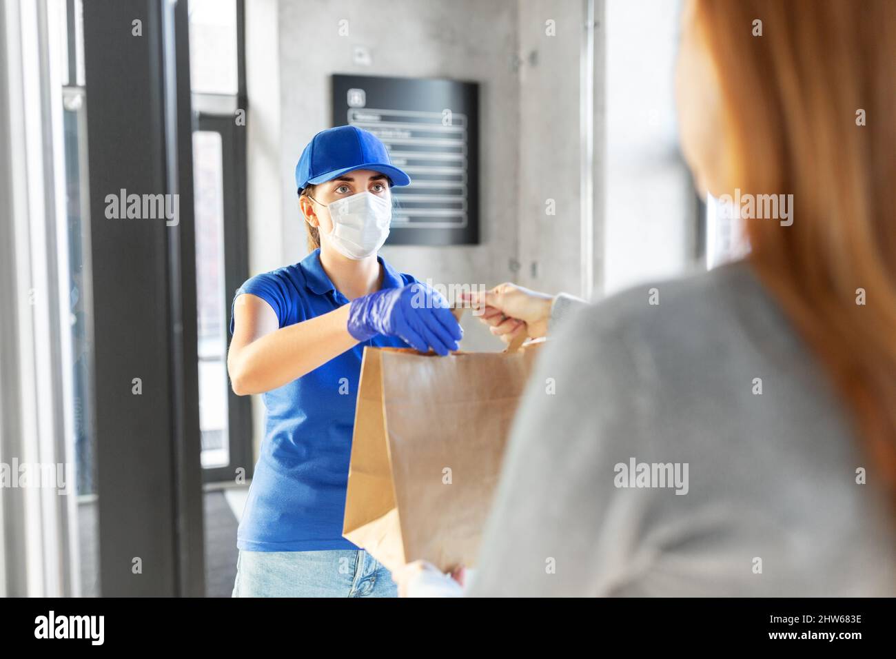 delivery girl in mask giving paper bag to customer Stock Photo - Alamy