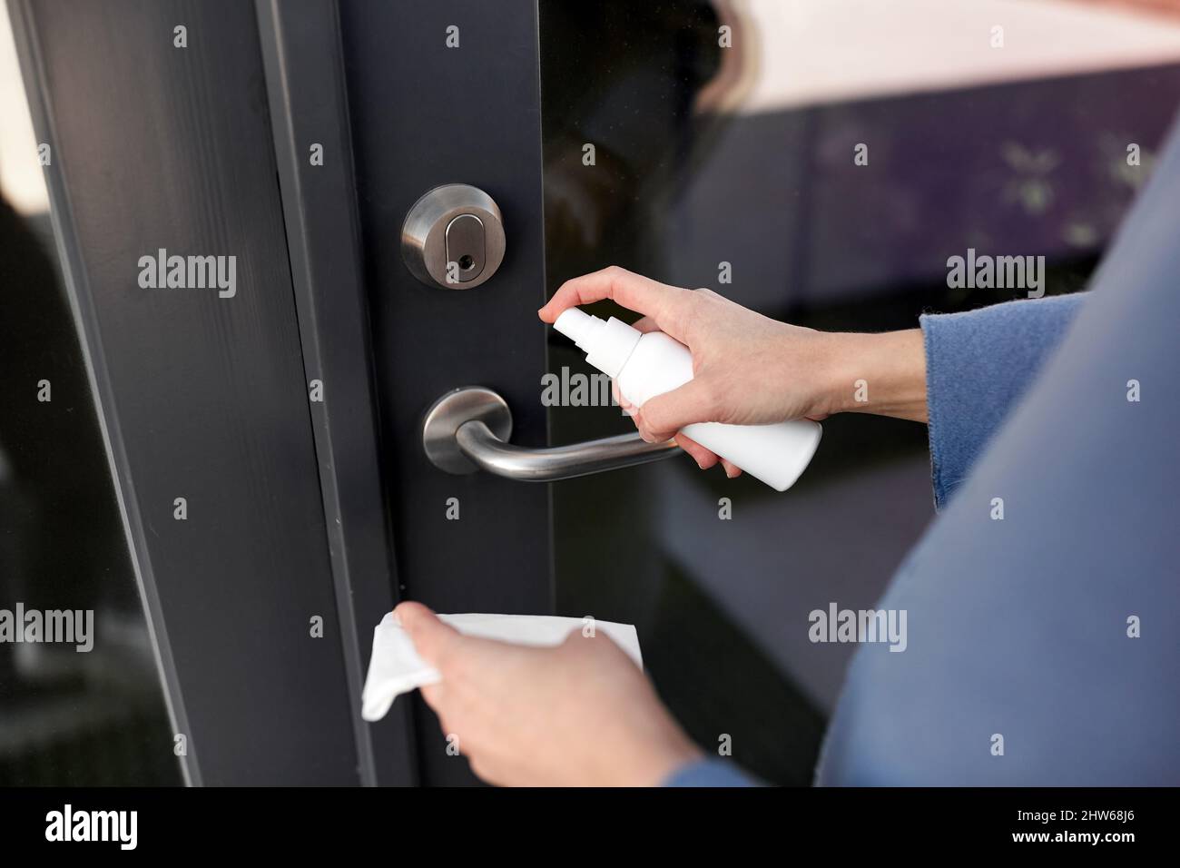 hand cleaning door handle with disinfectant spray Stock Photo