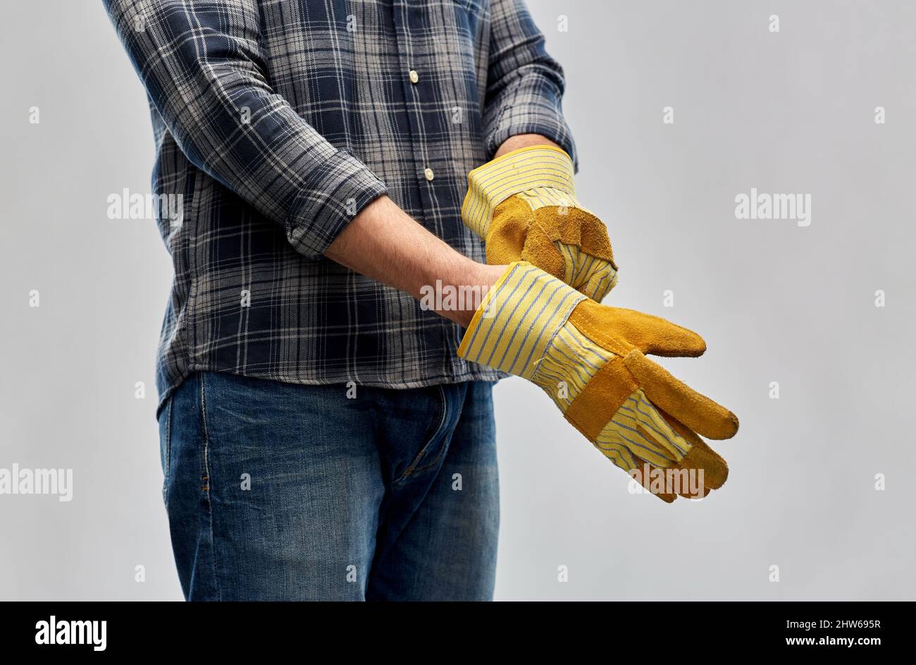 man or builder putting protective gloves on Stock Photo