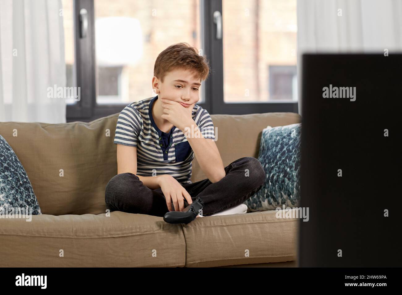 sad boy with gamepad playing video game at home Stock Photo