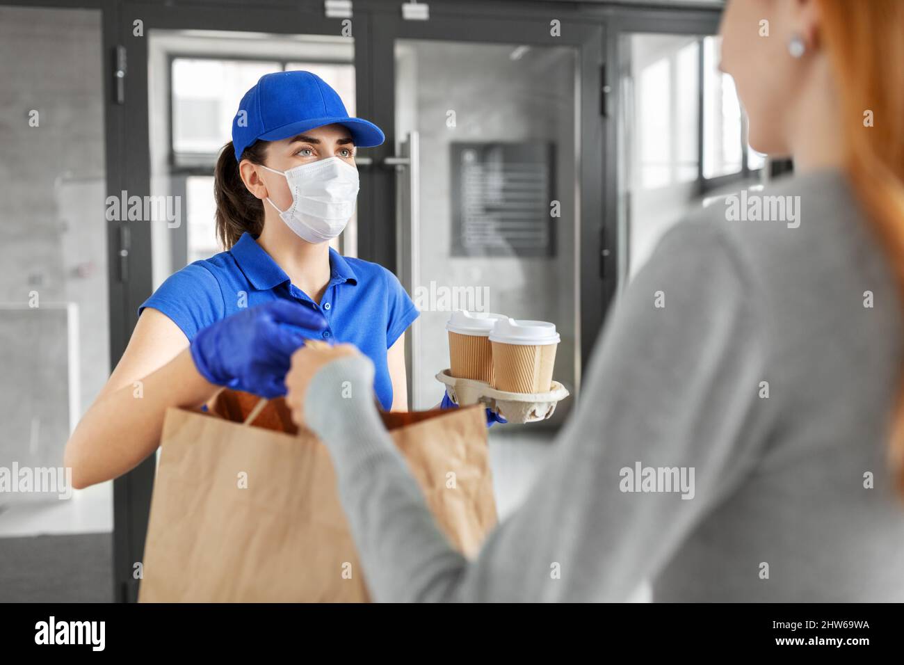 delivery girl in mask giving paper bag to customer Stock Photo - Alamy