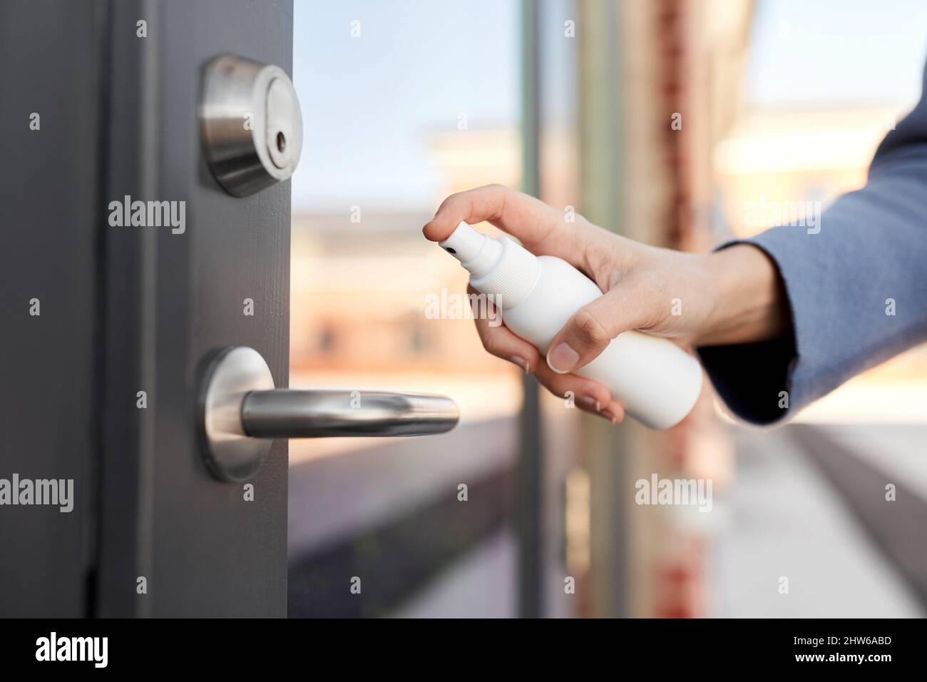 hand cleaning door handle with disinfectant spray Stock Photo