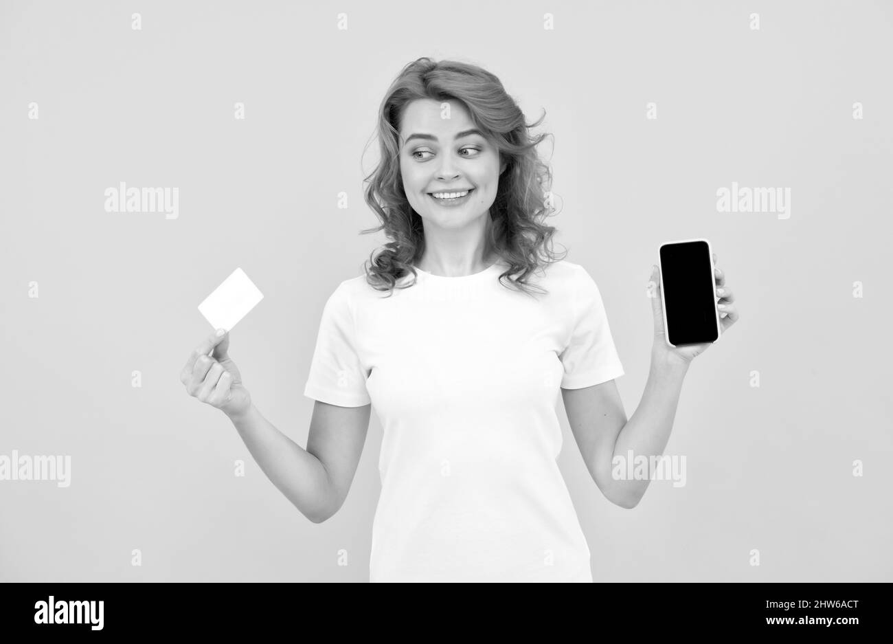 happy woman showing credit or debit card and smartphone to make online shopping, payment online. Stock Photo
