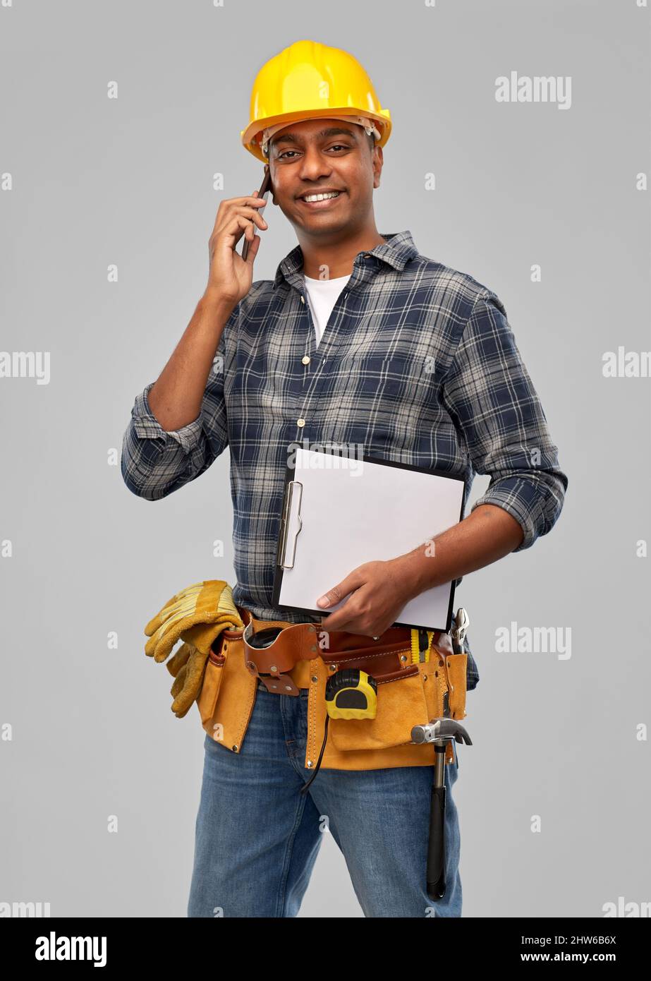indian builder in helmet calling on smartphone Stock Photo