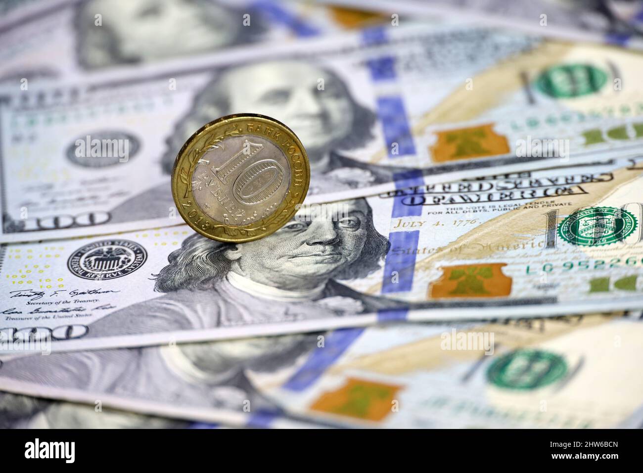 Russian rubles coin on background of US dollars. Concept of exchange rate, sanctions, falling ruble Stock Photo