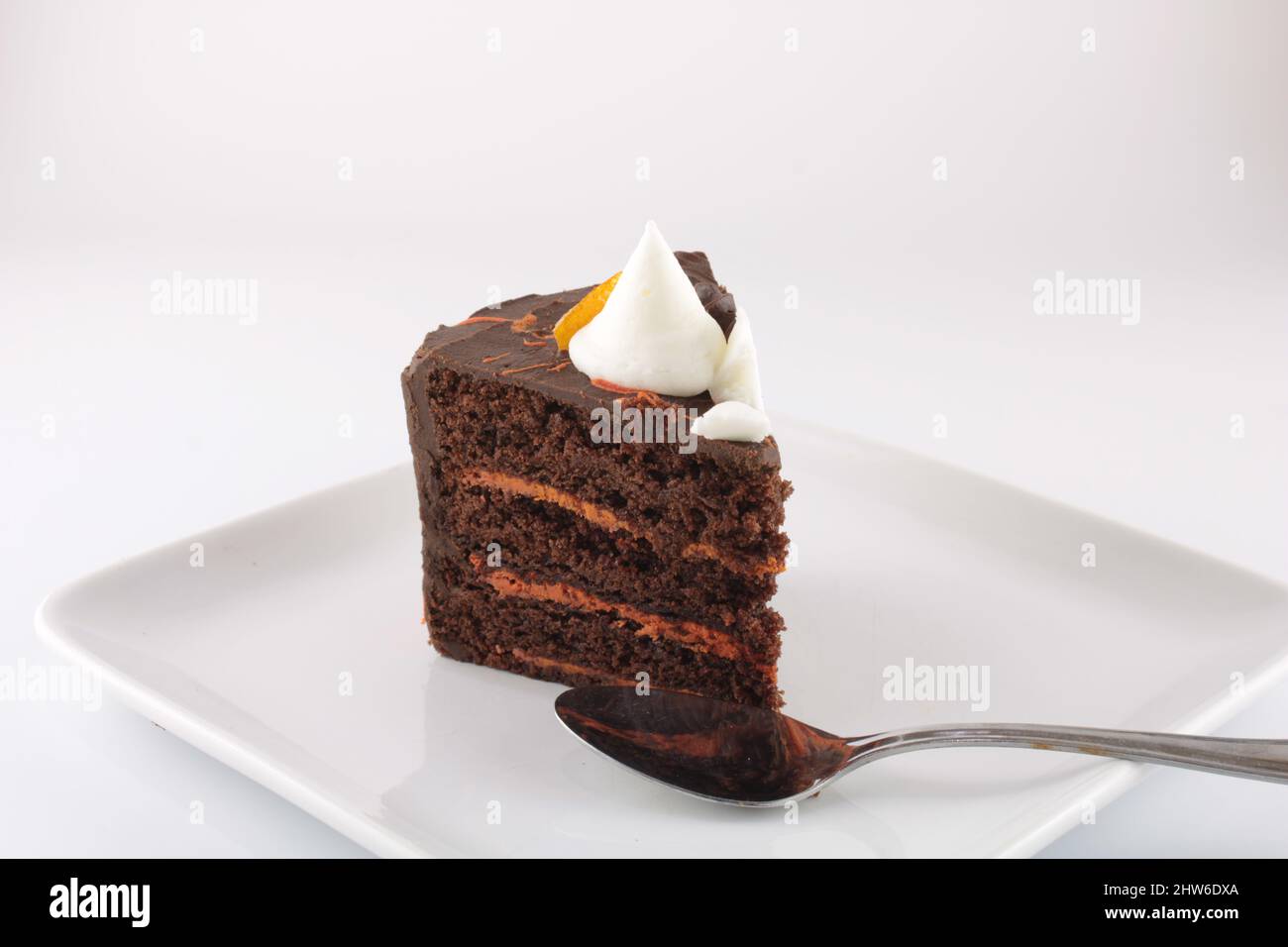 Slice of dark rich chocolate orange cake isolated on a plate with copy space. Obesity concept Stock Photo
