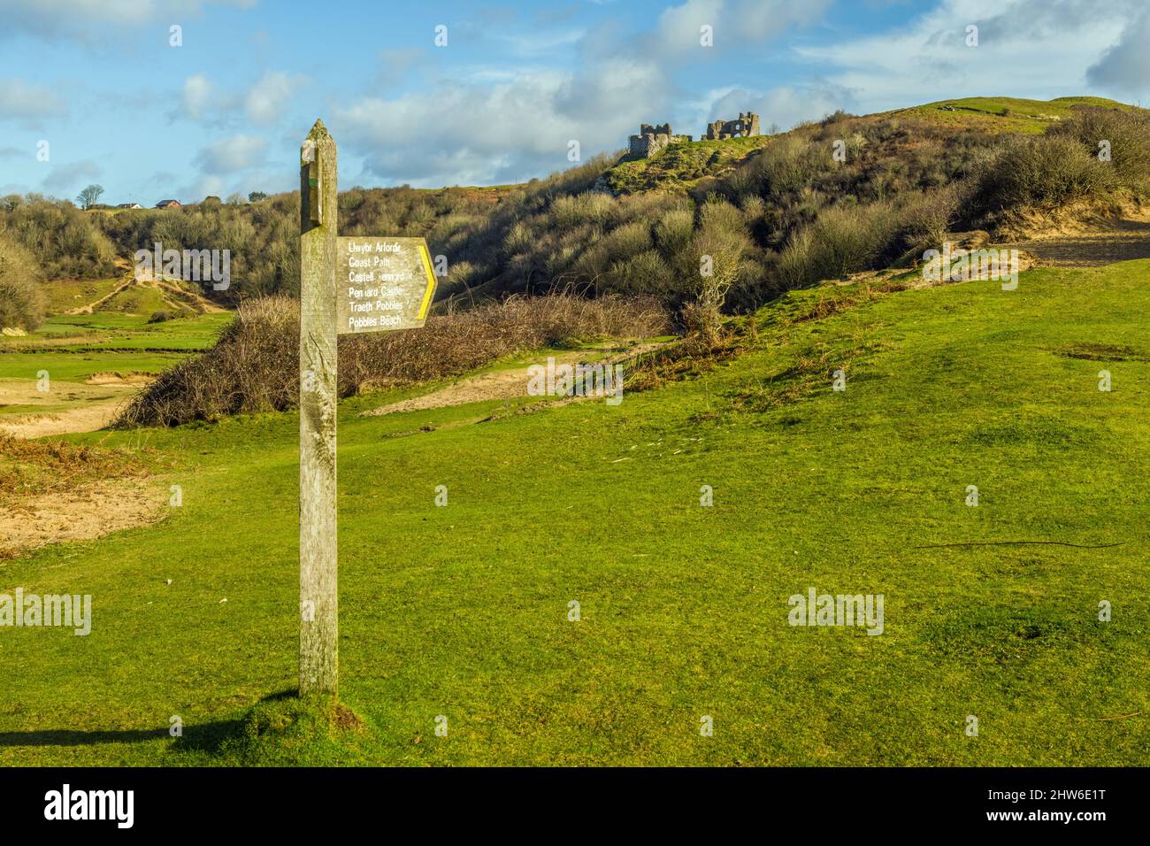 Pennard Castle remains up on the dune tops with a finger post below on the way to Three Cliffs Bay Stock Photo