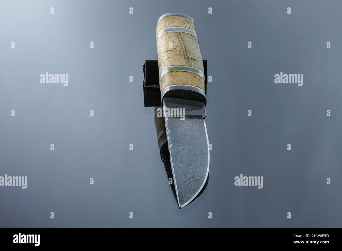 Handmade carving knife on a mirrored surface, damascus blade, wood