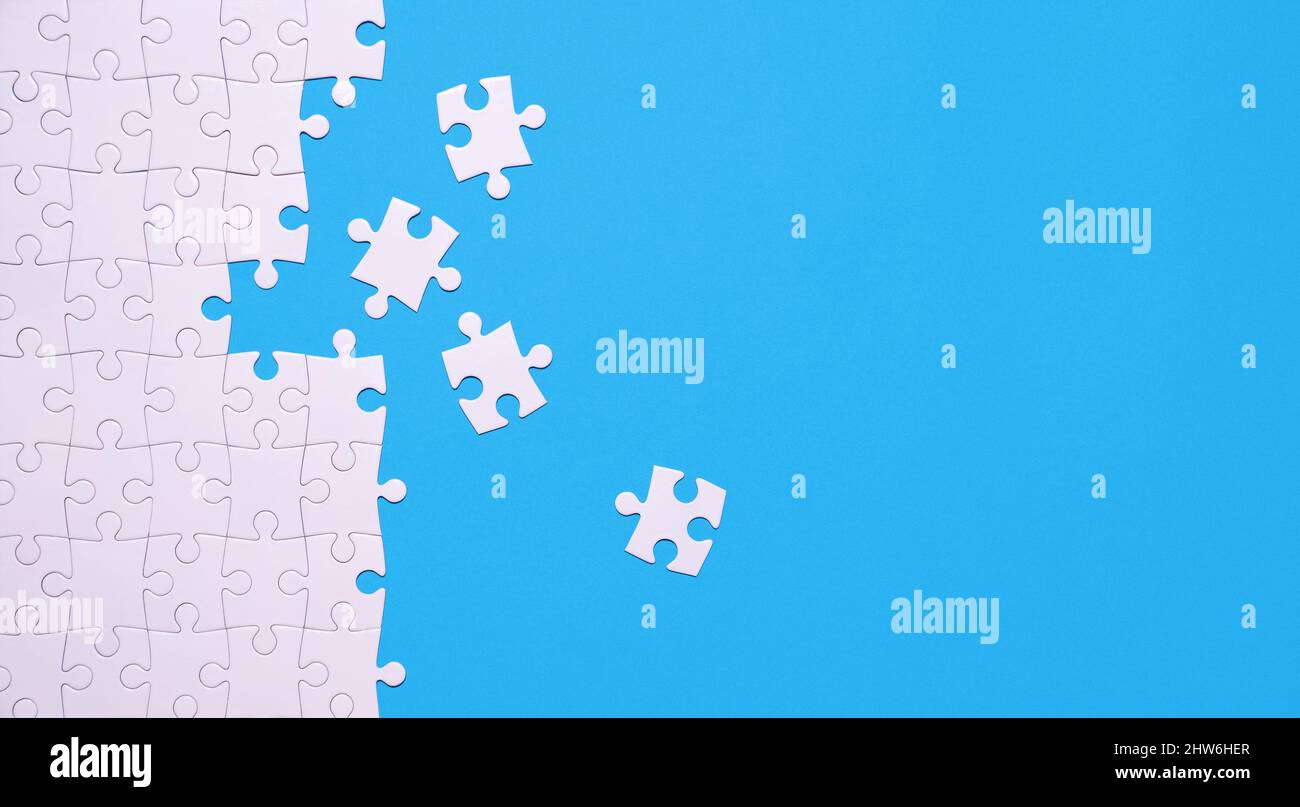 Unfinished white jigsaw puzzle isolated on blue background with copy space Stock Photo