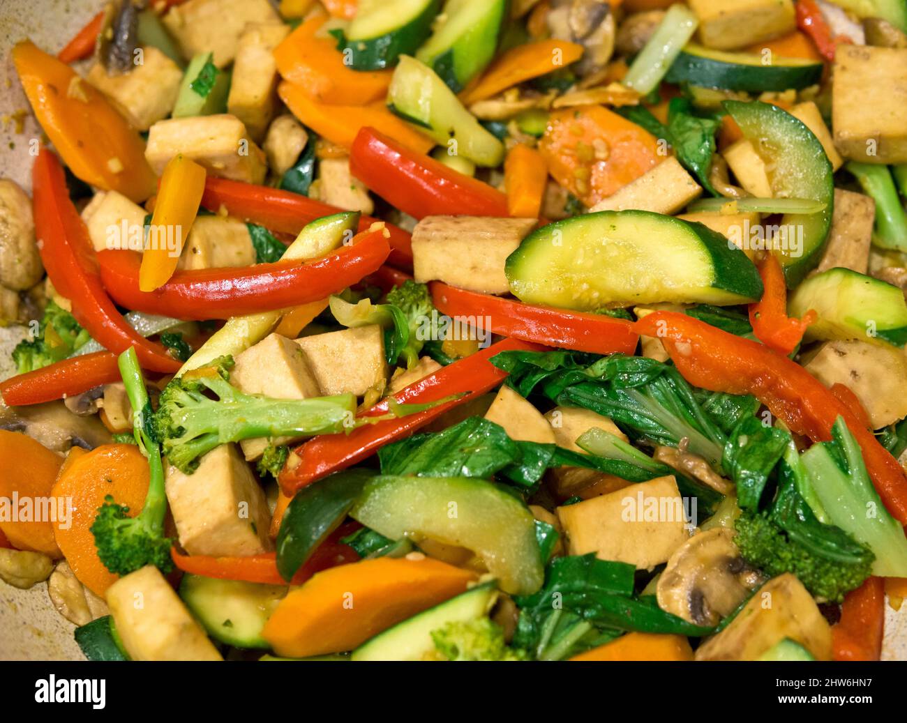 Tofu stir fry with red bell peppers, zucchini, carrots, and bok choy.  Tofu and vegetables in a pan. Stock Photo
