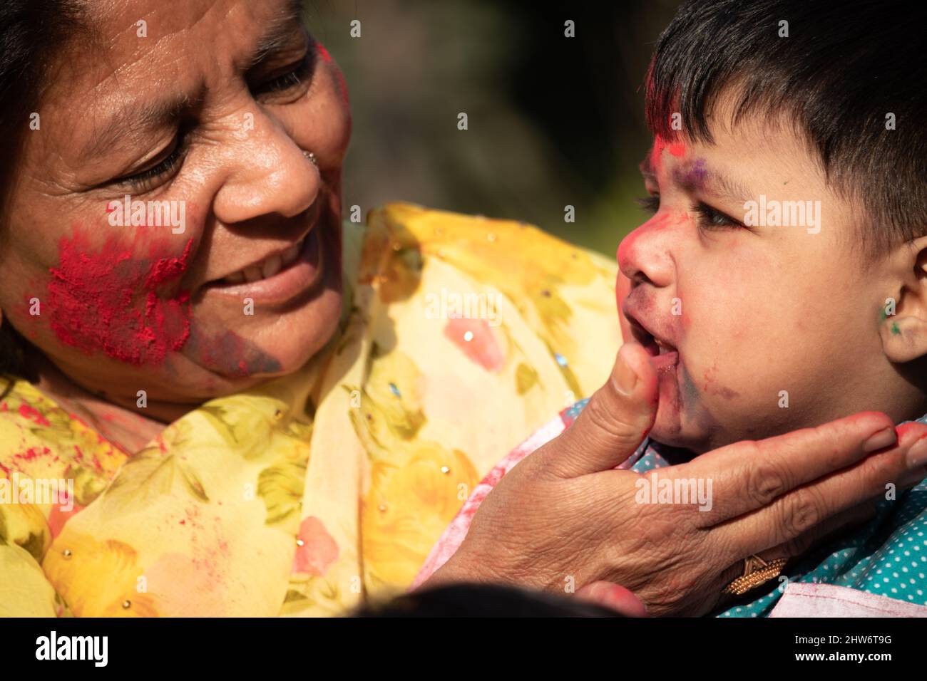 Elderly Indian Lady And Kid Enjoying Holi With Gulal Or Abir Rang Abeer. Festive, Family, Fun, Celebration, Enjoyment, Togetherness, Multi Generation Stock Photo