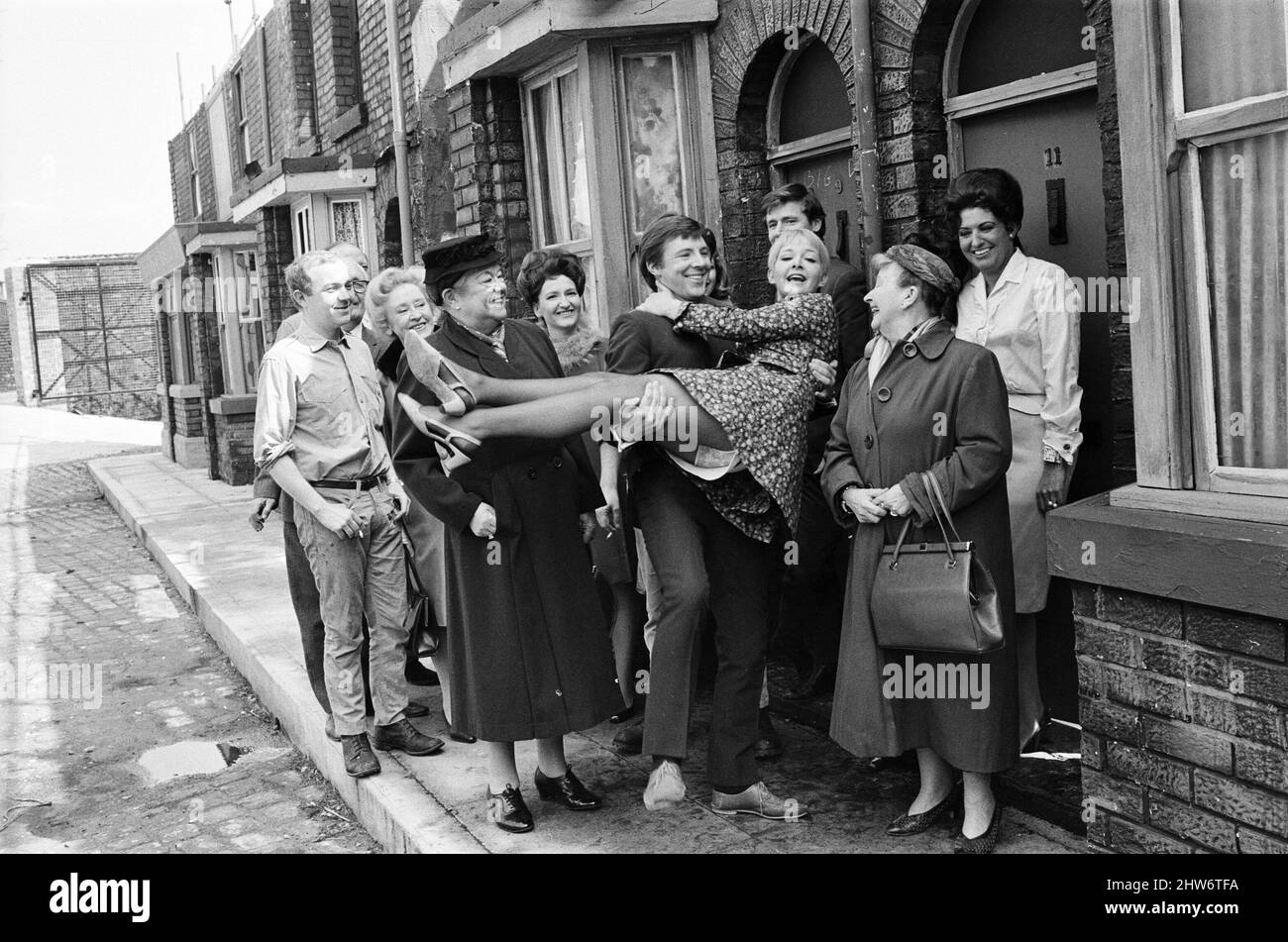 A new street setting for 'Coronation Street'. Granada TV have built an outdoor set for shooting some of the scenes. Pictured are cast members:  Cast member Dennis Tanner (Philip Lowrie) with his bride Jenny Sutton (Mitzi Rogers) after their wedding with Annie Walker (Doris Speed), Ena Sharples (Violet Carson), Emily Nugent (Eileen Derbyshire), Ken Barlow (William Roache) and Elsie Tanner (Pat Phoenix). 18th May 1968. Stock Photo