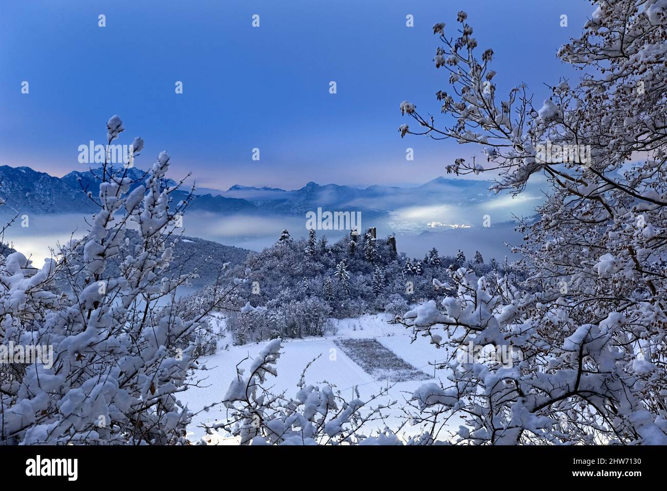 The Gresta Valley on a full moon winter night: in the center the hill where the medieval ruins of Gresta Castle stand. Pannone, Trentino, Italy. Stock Photo