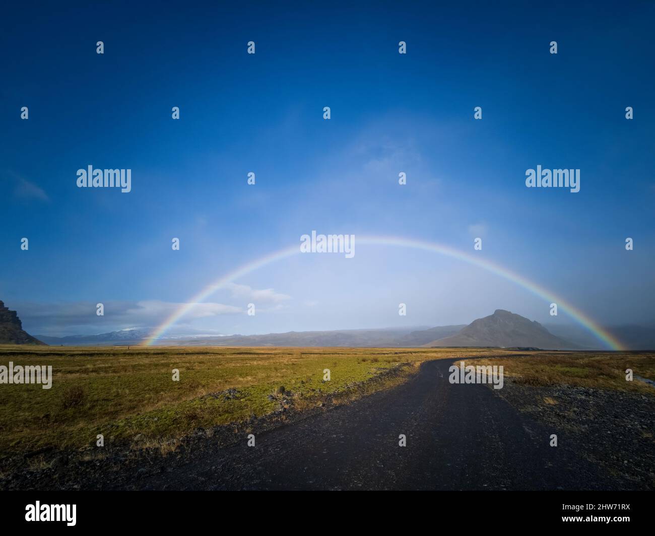 Curved track, rainbow and mountains under clear blue sky Stock Photo