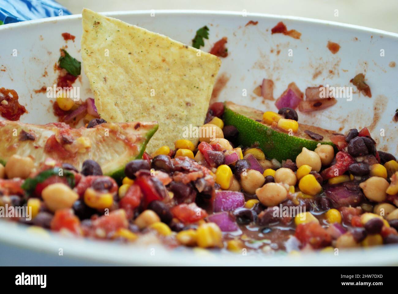 Fresh black bean and corn dip in a large serving bowl with tortilla