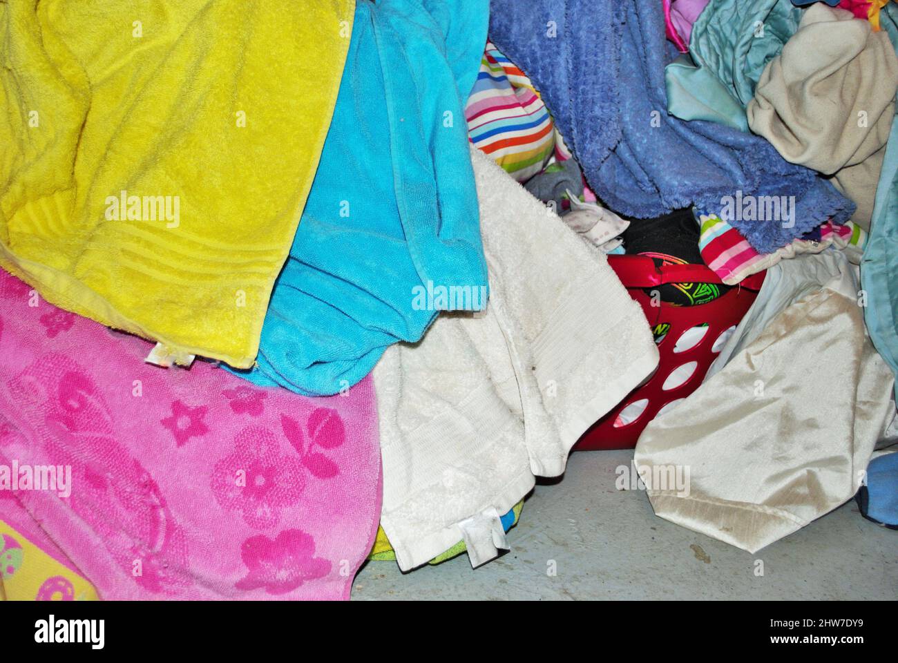 Pile of dirty towels that need to be washed in a basement laundry room