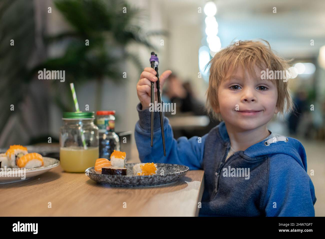 Child, eating japanese sushi and noodles with chopsticks in a restaurant, dinnertime Stock Photo