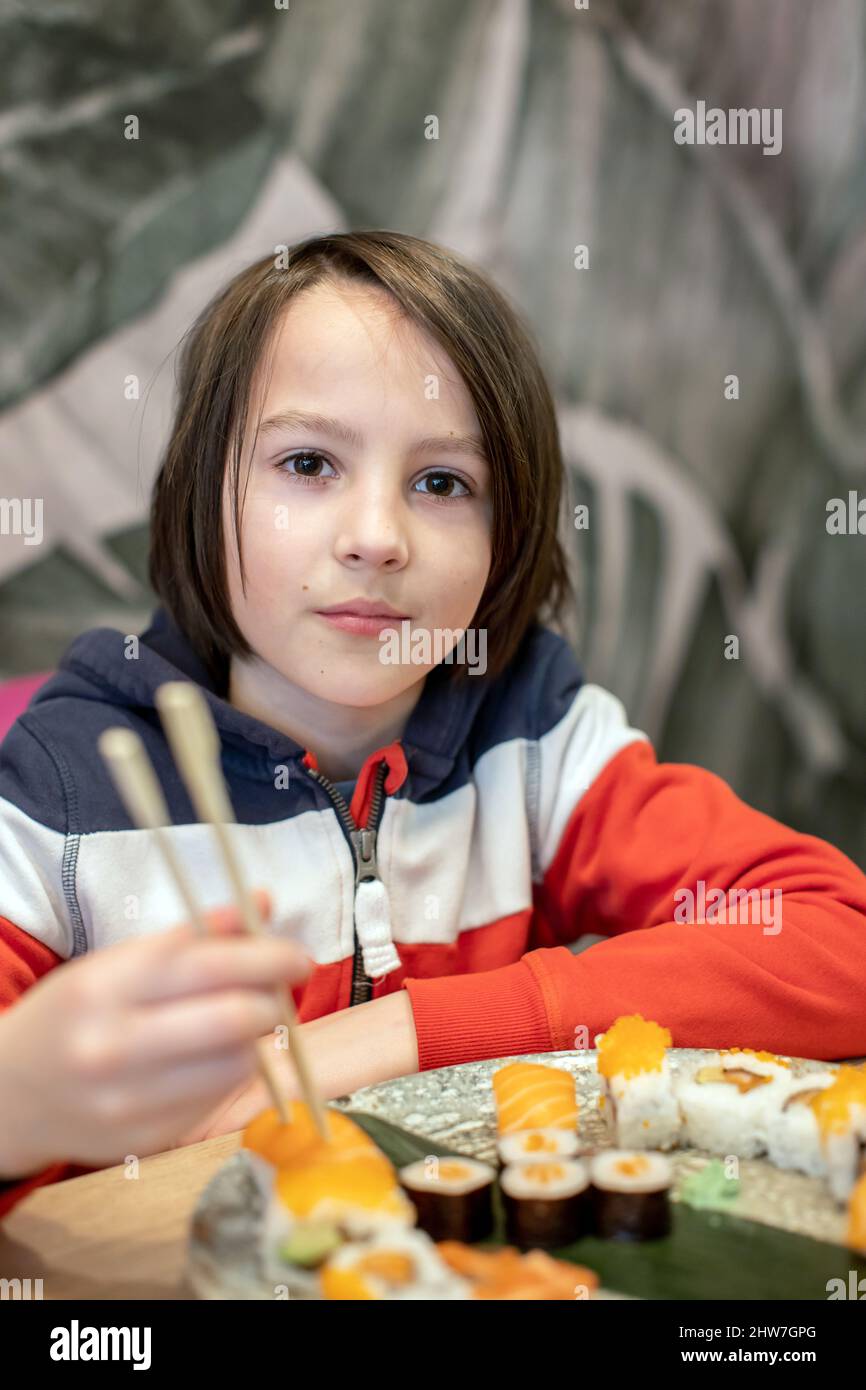 Child, eating japanese sushi and noodles with chopsticks in a restaurant, dinnertime Stock Photo