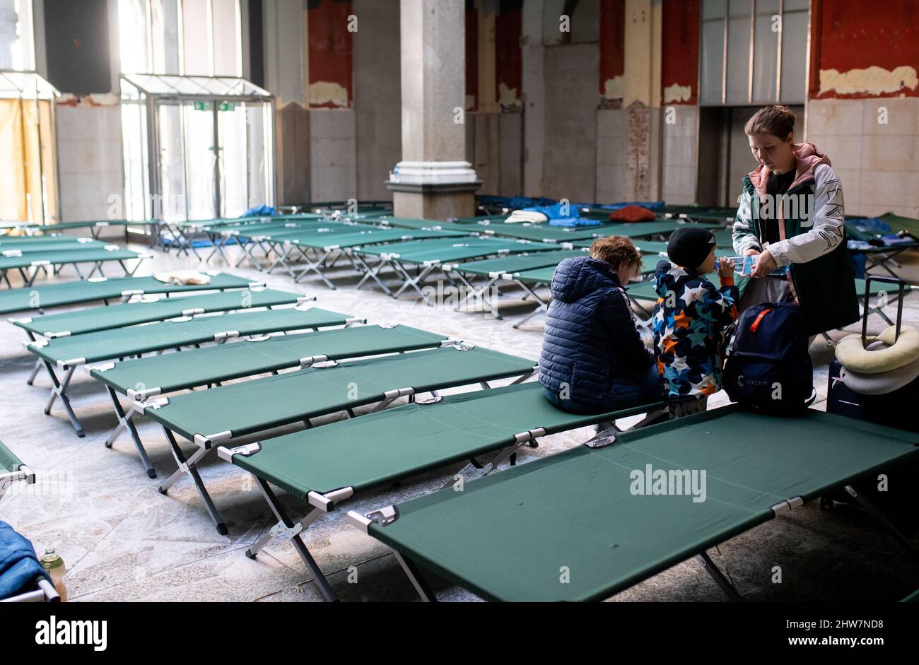 Munich, Germany. 04th Mar, 2022. Svitlana (r), who fled the Ukrainian capital Kiev with her son Roman and her mother Tetiana, wait in a hall with cots after arriving at the main train station. Credit: Sven Hoppe/dpa/Alamy Live News Stock Photo