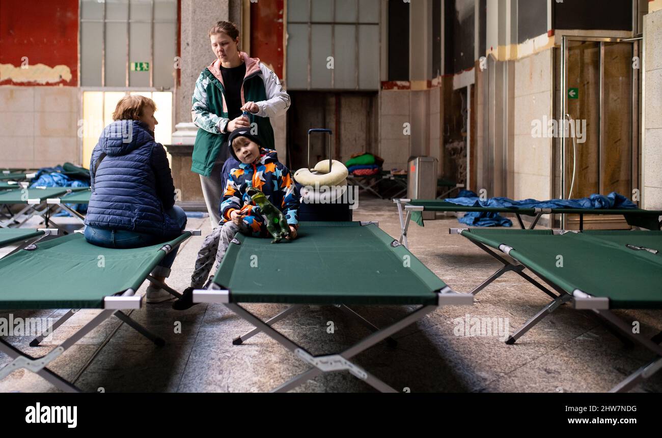 Munich, Germany. 04th Mar, 2022. Svitlana (M), who fled the Ukrainian capital Kiev with her son Roman and her mother Tetiana, wait in a hall with cots after arriving at the main train station. Credit: Sven Hoppe/dpa/Alamy Live News Stock Photo