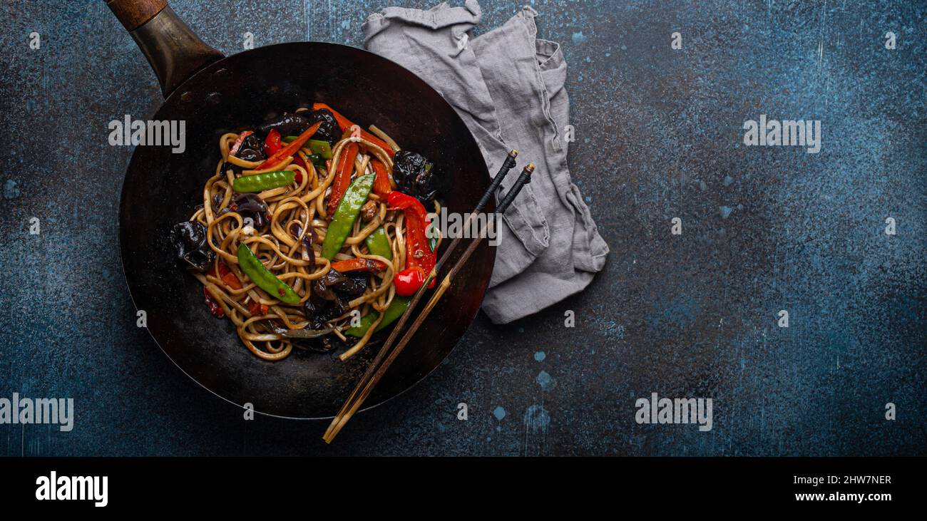 Asian stir fry noodles with vegetables in black wok pan copy space Stock Photo