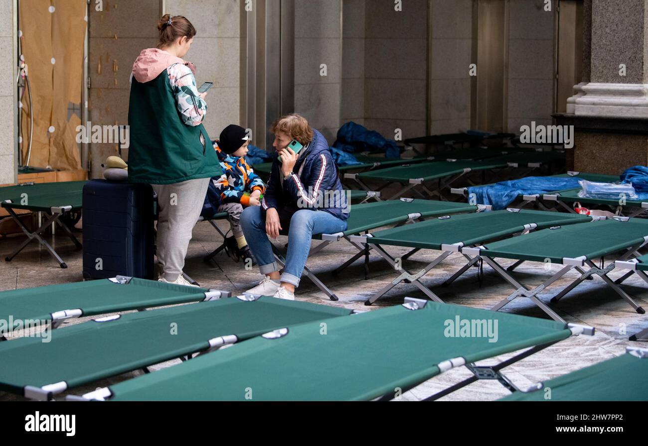 Munich, Germany. 04th Mar, 2022. Svitlana (l), who fled the Ukrainian capital Kiev with her son Roman and her mother Tetiana, wait in a hall with cots after arriving at the main train station. Credit: Sven Hoppe/dpa/Alamy Live News Stock Photo