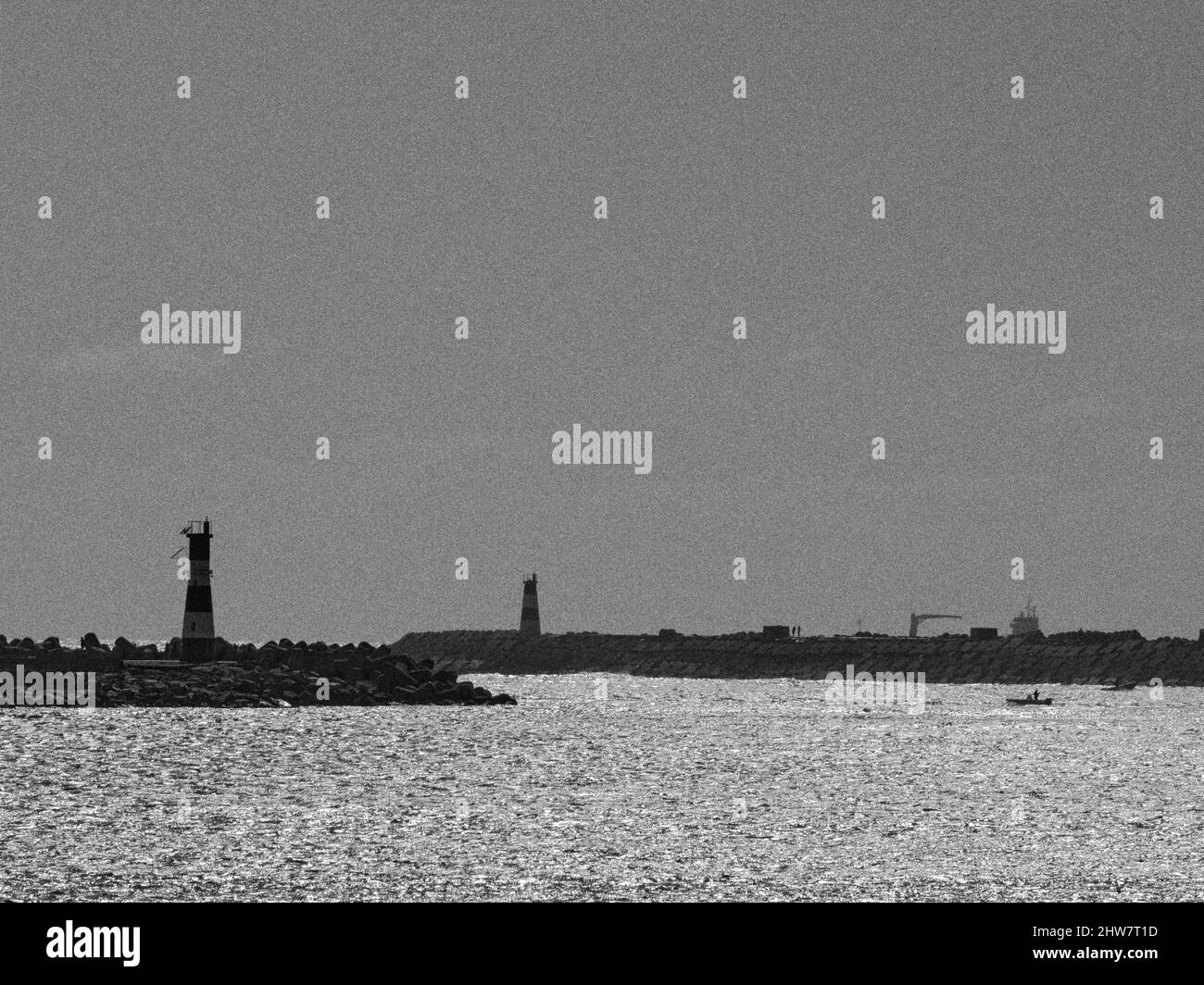 Grayscale of spurs and lighthouses against the seascape on Barra beach, Aveiro, Portugal Stock Photo