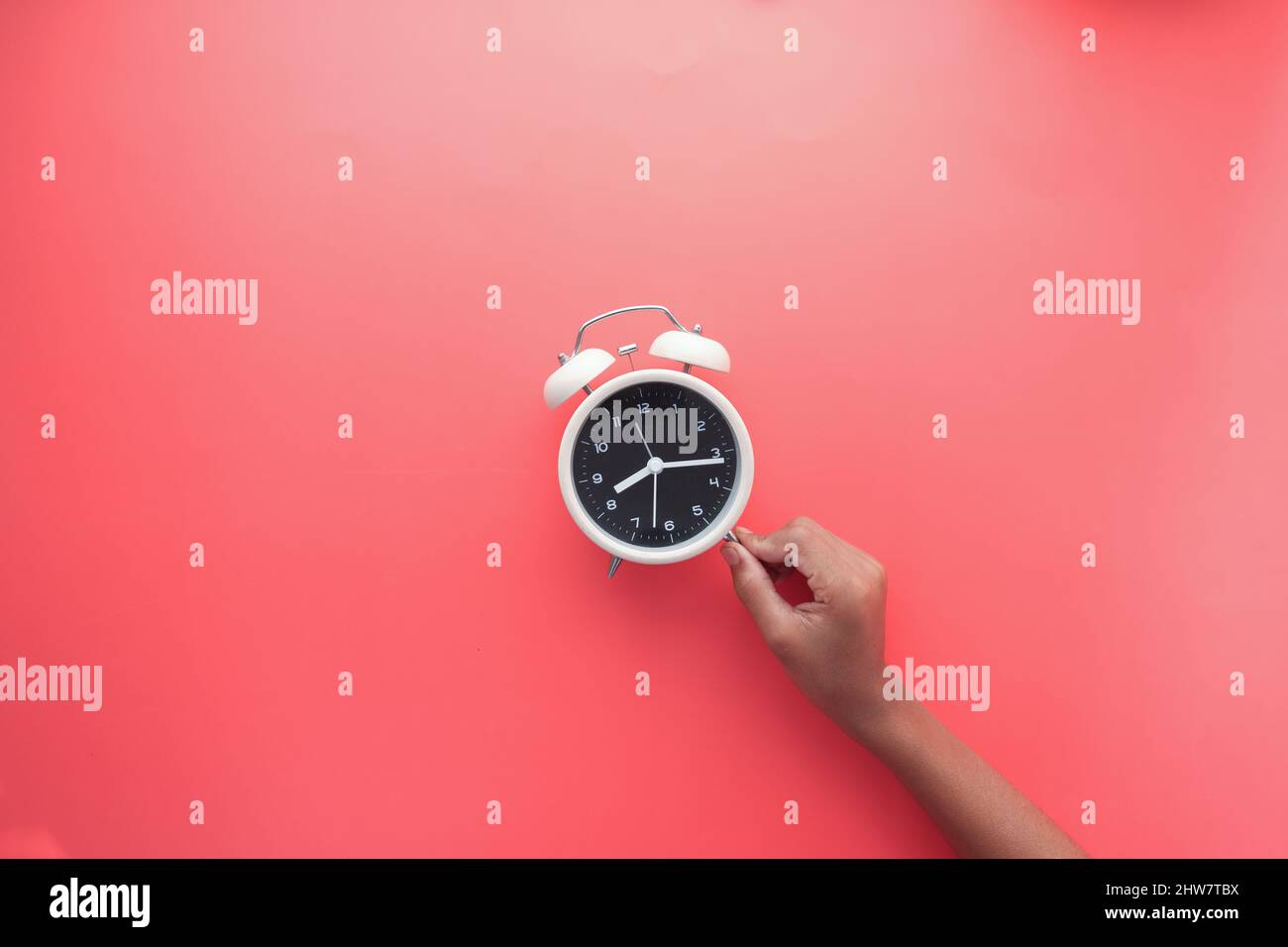 holding a old alarm clock on red background. Stock Photo