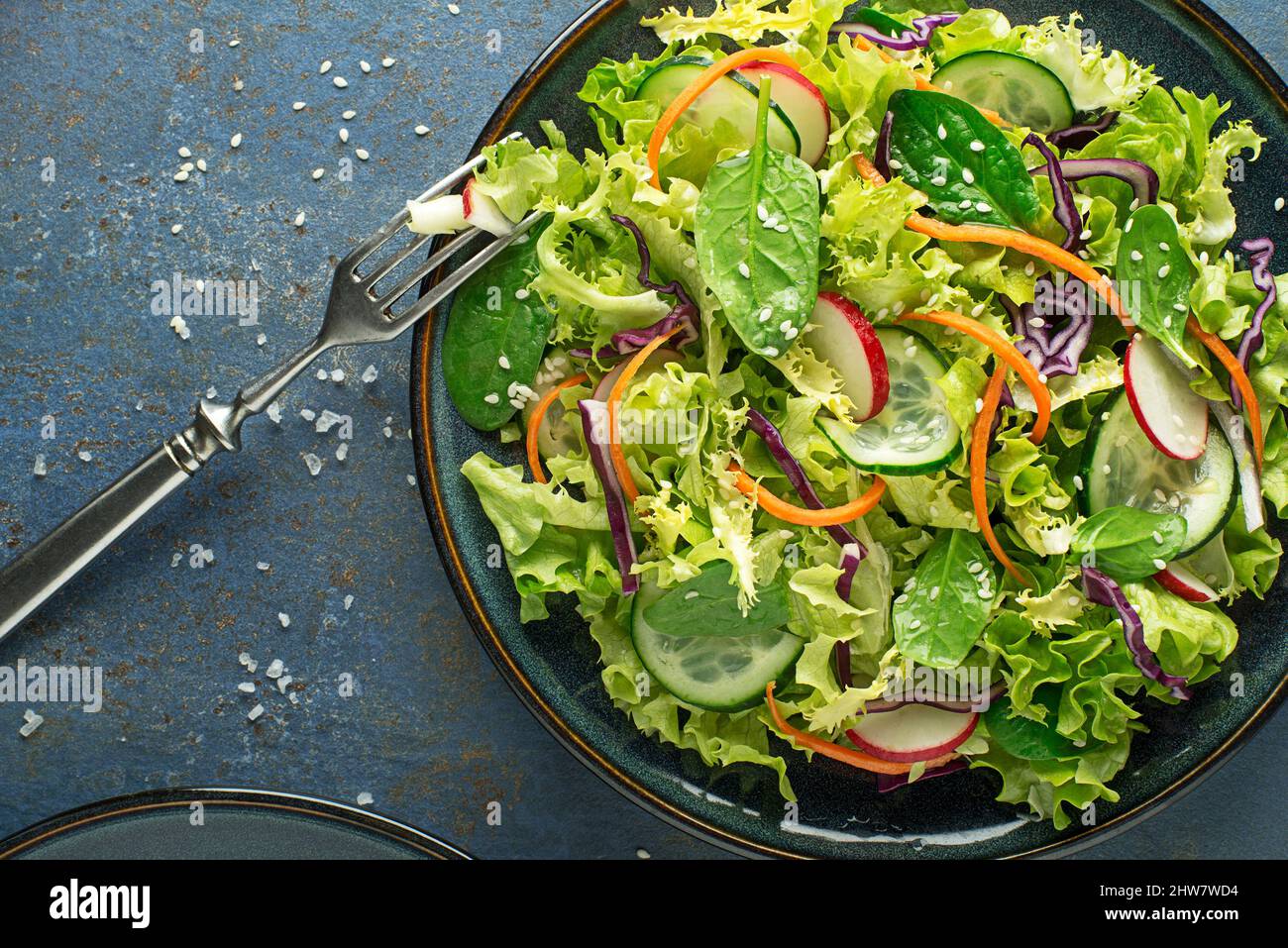 Green lettuce salad meal with fresh mixed vegetables on blue table background Stock Photo